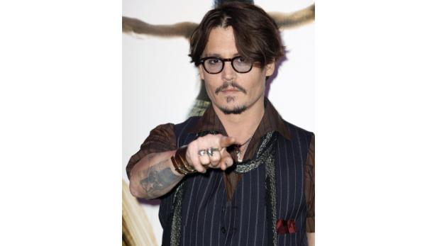 Johnny Depp mit Brille und Bart deutet mit dem Finger auf den Betrachter.