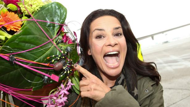 Eine Frau zeigt auf einen Blumenstrauß, der mit Spielzeugspinnen dekoriert ist.