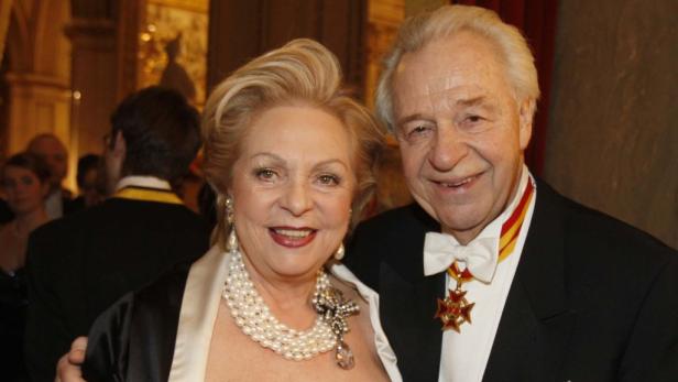 Ein älteres Paar in Abendgarderobe lächelt in die Kamera.