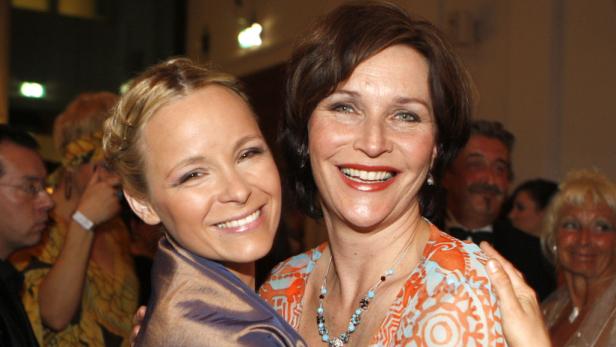 Zwei Frauen lächeln in die Kamera, eine mit blonden, die andere mit braunen Haaren.