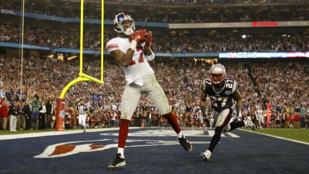 Ein Wide Receiver fängt einen Pass während eines American-Football-Spiels.