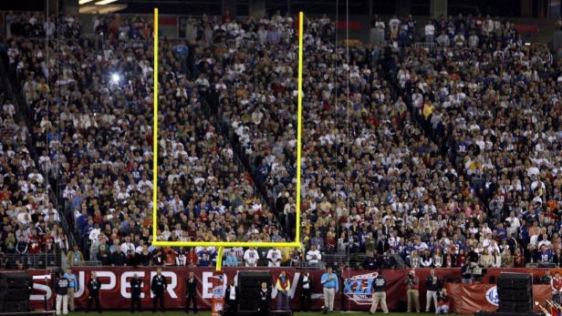 Ein volles Footballstadion mit gelben Torstangen im Vordergrund.