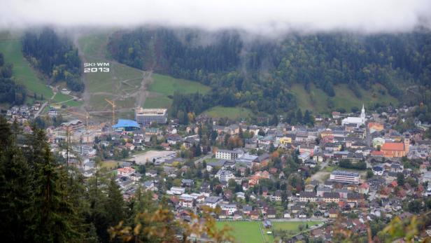 Blick auf eine Stadt in den Bergen mit der Aufschrift „SKI-WM 2013“ auf einem Hang.