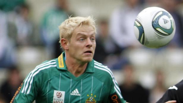 Ein Fußballspieler mit blonden Haaren blickt auf einen Ball in der Luft.