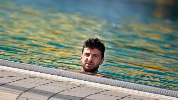 Ein Mann steht bis zum Hals im Wasser eines Schwimmbeckens.