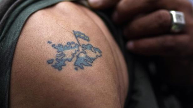Ein Tattoo der Falklandinseln mit Flagge auf der Schulter einer Person.