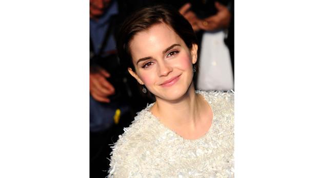 Emma Watson lächelt in einem weißen Kleid.