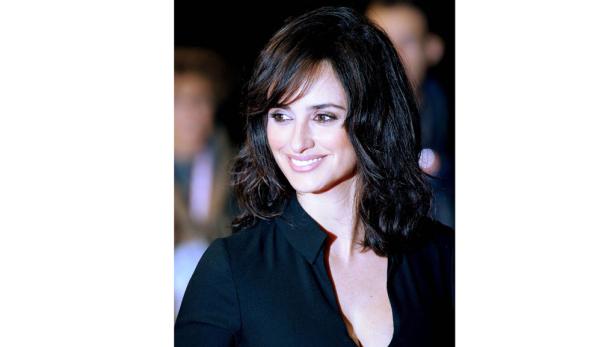 Porträt von Penélope Cruz mit dunklem, gewelltem Haar und einem schwarzen Oberteil.