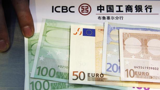 Verschiedene Euro-Banknoten liegen vor dem Logo der ICBC Bank.
