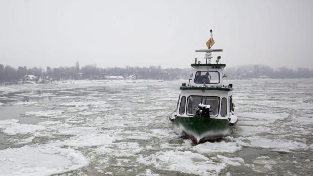 Ein grünes Boot fährt durch eine eisige Wasserfläche.