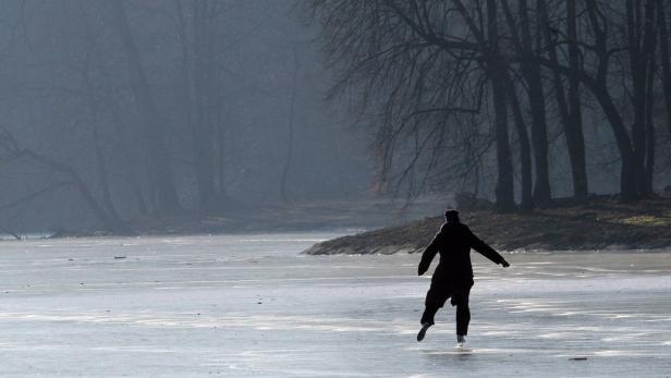 Eine Person läuft Schlittschuh auf einem zugefrorenen See im Winter.