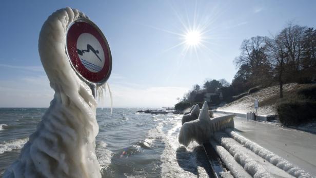 Ein mit Eis bedecktes Schild, das das Springen ins Wasser verbietet, an einem sonnigen Tag.