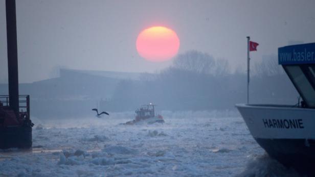 Ein Schiff namens „Harmonie“ fährt durch eisiges Wasser bei Sonnenaufgang.