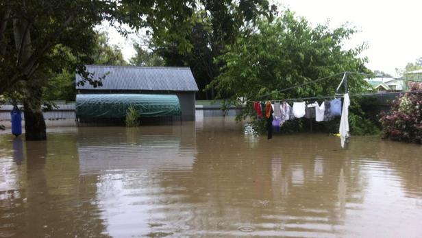 Ein überfluteter Garten mit einem Schuppen und einer Wäscheleine unter Wasser.