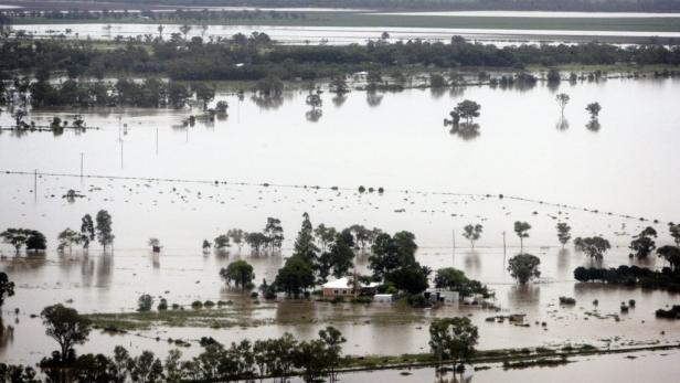 Überschwemmtes Farmland mit einem Haus, das fast vollständig von Wasser bedeckt ist.