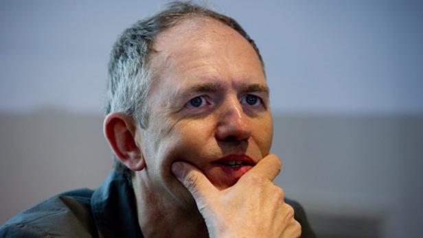 Ein Mann mittleren Alters mit grauen Haaren und nachdenklichem Gesichtsausdruck.