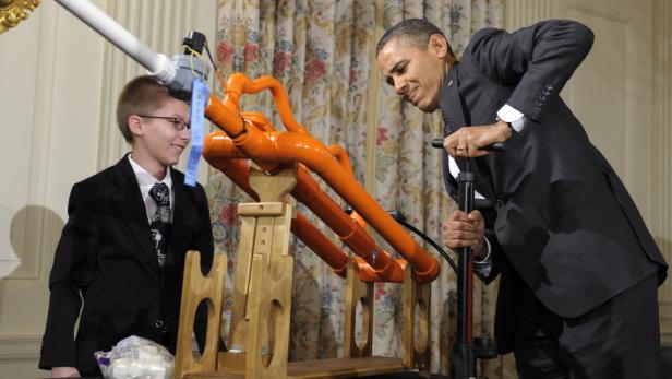 Barack Obama bedient eine Marshmallow-Kanone, während ein junger Mann zusieht.