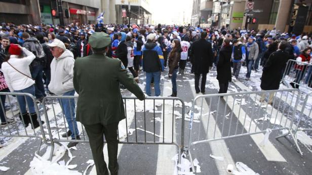 Eine Menschenmenge feiert auf einer Straße, die mit Konfetti bedeckt ist.