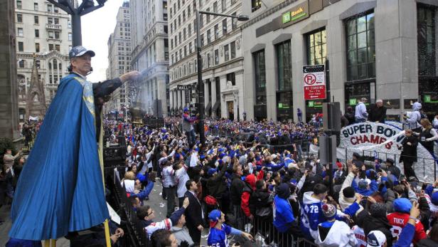 Ein Mann in einem blauen Umhang schwenkt ein Räuchergefäß bei der Super Bowl-Parade in New York City.