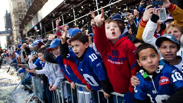 Jungen in Giants-Trikots feiern bei einer Parade mit Konfetti.