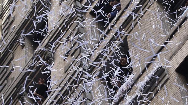 Konfetti fällt aus den Fenstern eines Bürogebäudes.