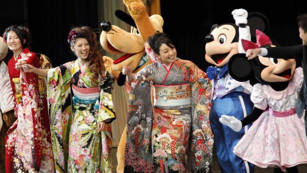 Frauen in Kimonos posieren mit Goofy, Mickey und Minnie Maus.