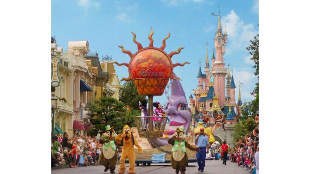Eine Parade mit Chip, Chap, Pluto und Micky Maus vor dem Dornröschenschloss in Disneyland.