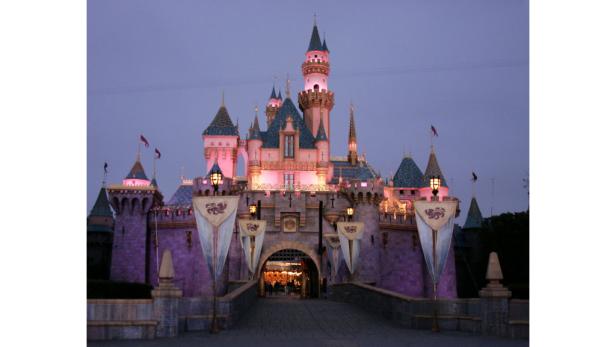 Das Dornröschenschloss im Disneyland ist bei Dämmerung beleuchtet.