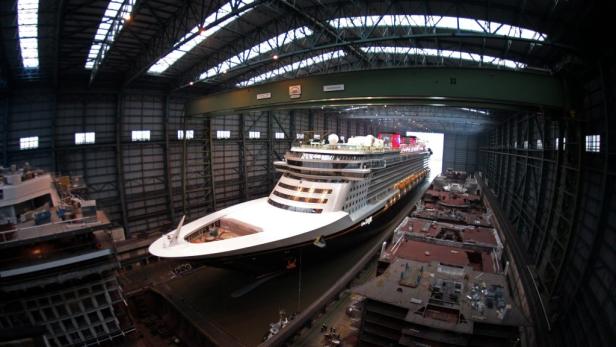 Ein Kreuzfahrtschiff im Trockendock unter einem Hallenkran.