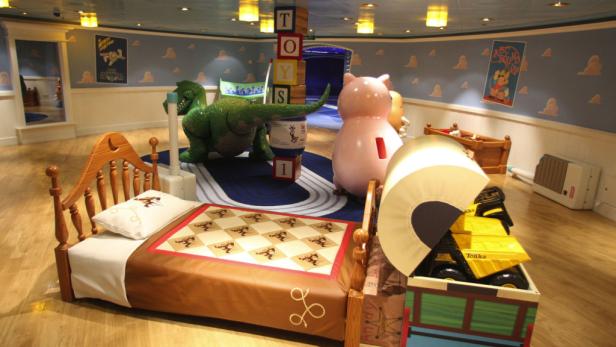 Ein Zimmer im „Toy Story“-Stil mit übergroßen Spielzeugfiguren wie Rex und Hamm.