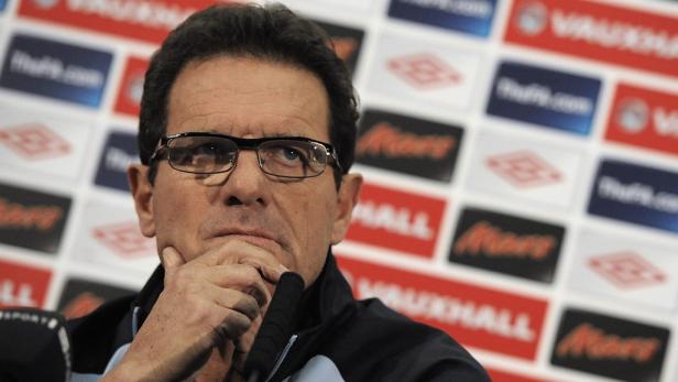 Fabio Capello bei einer Pressekonferenz mit seiner Hand am Kinn.