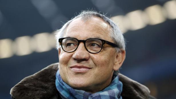 Ein Mann mit Brille und Schal blickt lächelnd zur Seite.