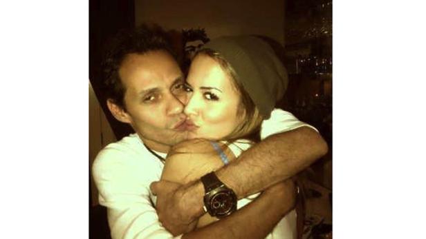 Ein Mann umarmt eine Frau mit Mütze, beide machen einen Kussmund.