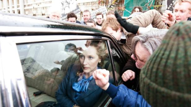 Meryl Streep als Margaret Thatcher im Auto, umringt von Demonstranten.