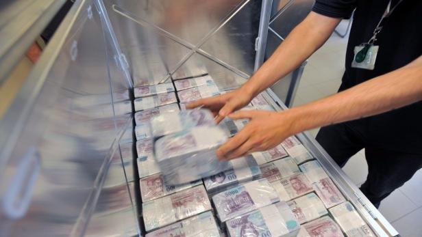 Ein Mann hantiert mit Bündeln ungarischer Forint-Banknoten in einem Tresor.