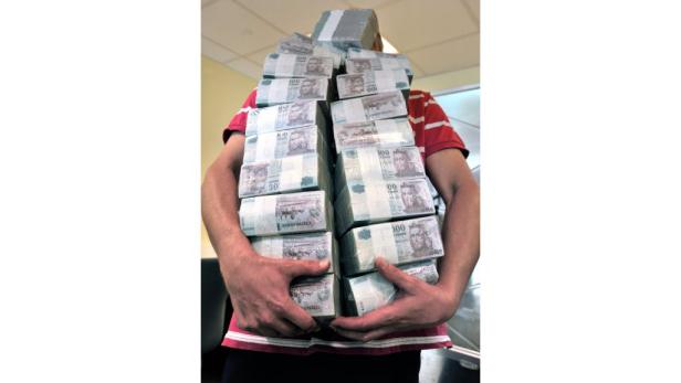 Eine Person hält mehrere Bündel ungarischer Forint-Banknoten.
