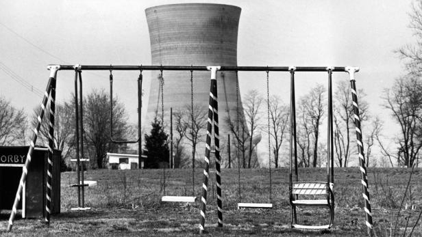 Eine Schaukel steht vor einem Kühlturm in einem verlassenen Park.