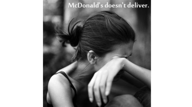 Eine weinende Frau sitzt mit dem Schriftzug „McDonald's doesn't deliver“ im Hintergrund.