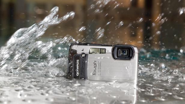 Eine wasserdichte Olympus-Kamera wird mit Wasser bespritzt.