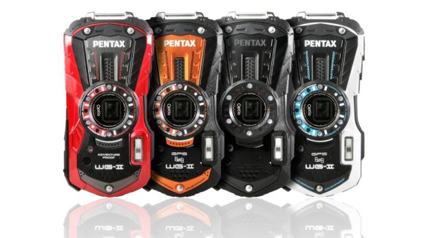 Vier robuste Pentax WG-II Kameras in Rot, Orange, Schwarz und Weiß stehen nebeneinander.