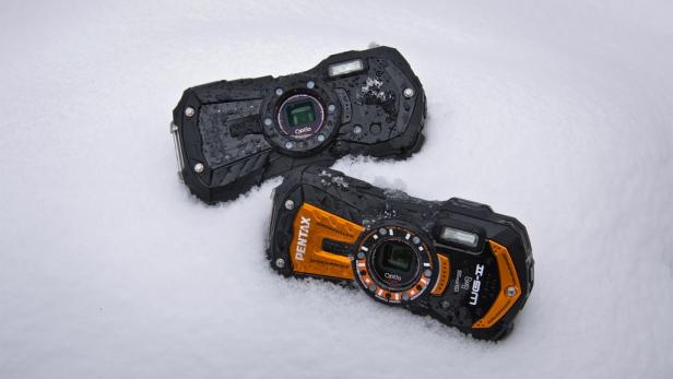 Zwei robuste Pentax Optio Kameras liegen im Schnee.