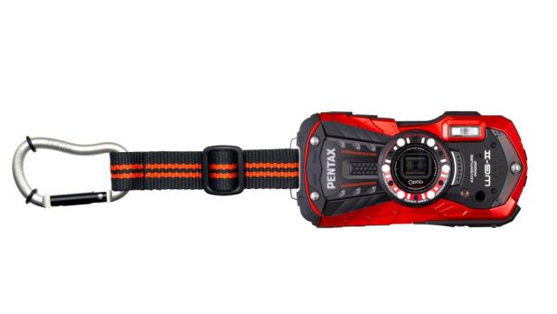 Eine rote Pentax WG-II Kompaktkamera mit Karabinerhaken und Trageschlaufe vor einem weißen Hintergrund.