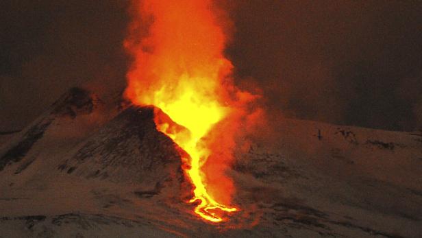 Ein Vulkan bricht aus und Lava fließt einen schneebedeckten Hang hinunter.