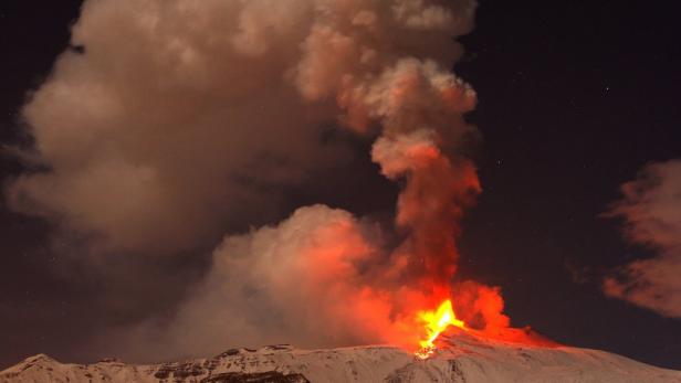 Ein Vulkan bricht nachts aus und speit Lava und Rauch in den Himmel.