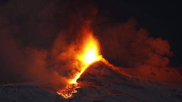 Ein Vulkan bricht nachts aus und speit Lava und Asche in den Himmel.