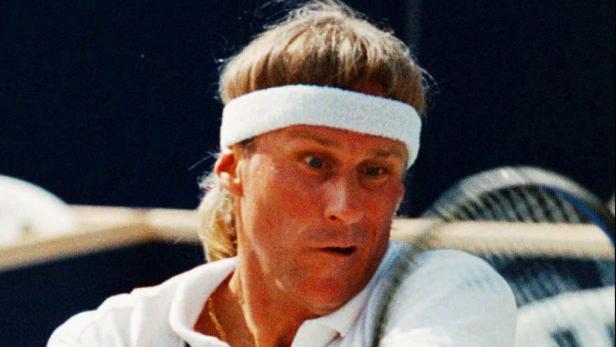 Ein Porträt von Björn Borg mit Stirnband auf einem Tennisplatz.