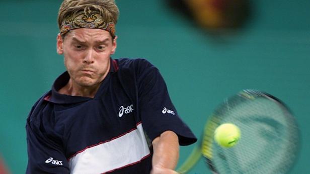 Ein Tennisspieler mit Stirnband schlägt einen Tennisball.