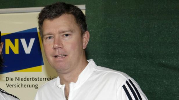 Ein Mann in einem weißen Sporthemd steht vor einem Banner der Niederösterreich Versicherung.