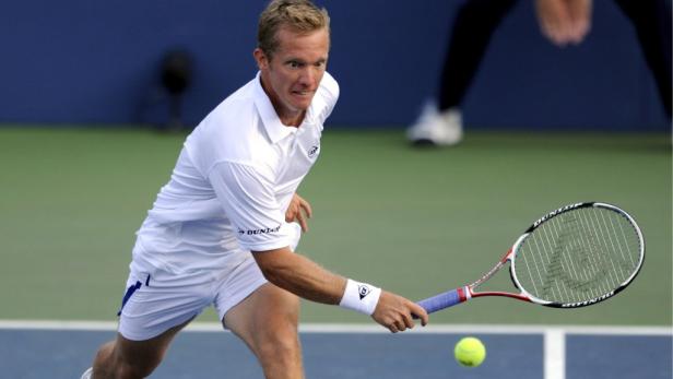 Ein Tennisspieler schlägt einen Ball auf einem Tennisplatz.