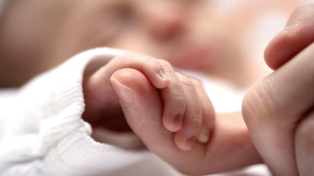 Ein Baby hält den Finger eines Erwachsenen fest.